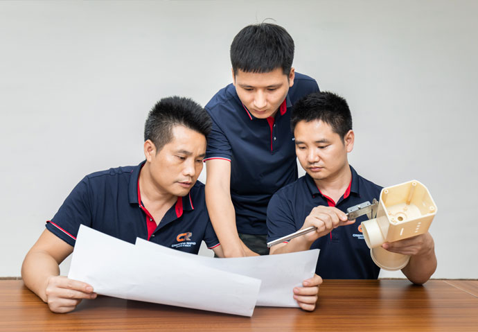 three engineers discussing molding project in front of a desk